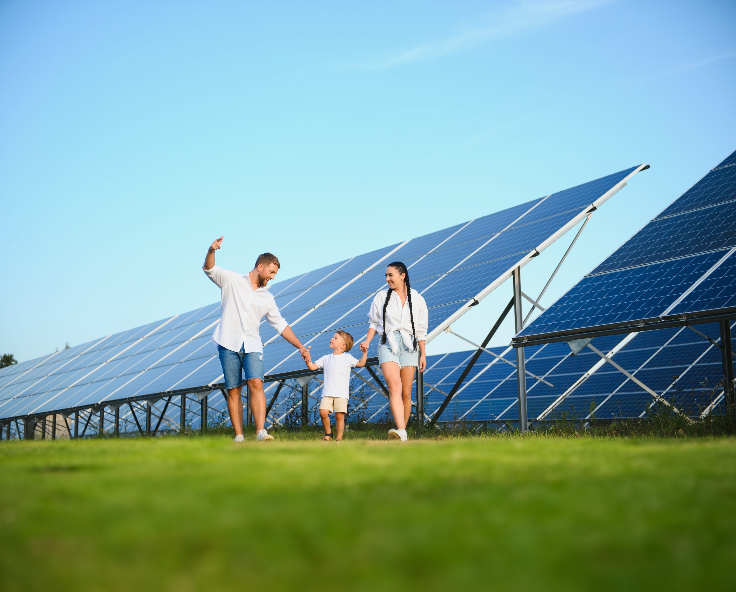 Young family of three is crouching near photovoltaic solar panel, little boy and parents. modern family concept. The concept of green energy.